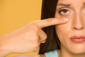 Woman pointing at herself wondering if lower eyelids can be droopy.