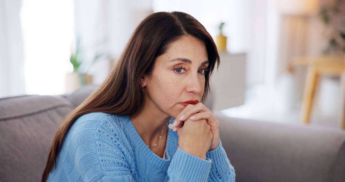 Woman, thinking and stress on sofa in home with financial crisis, jobless and overwhelmed with pressure. Person, thoughtful and worry on couch with depression, reflection and mortgage debt in lounge